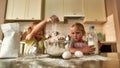 Two cute little children, boy and girl adding flour, milk and other ingredients while cooking, preparing dough together Royalty Free Stock Photo