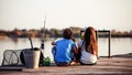 Two cute little friends, boy and girl eating sandwiches and fishing on a lake in a sunny summer day Royalty Free Stock Photo