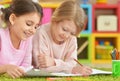 Two cute little girls drawing with pencils while lying on floor Royalty Free Stock Photo