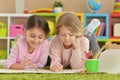 Two cute little girls drawing with pencils while lying on floor Royalty Free Stock Photo