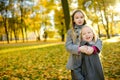 Two cute little girls having fun on beautiful autumn day. Happy children playing in autumn park. Kids gathering yellow fall foliag Royalty Free Stock Photo