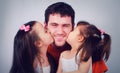 Two cute little girls kissing his happy dad