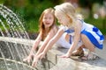 Two cute little girls playing with a city fountain on hot summer day Royalty Free Stock Photo