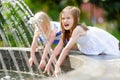 Two cute little girls playing with a city fountain on hot summer day Royalty Free Stock Photo