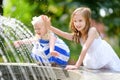 Two cute little girls playing with a city fountain on hot summer day Royalty Free Stock Photo