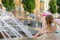 Two cute little girls playing by city fountain on hot and sunny summer day. Children having fun with water in summer. Royalty Free Stock Photo