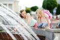 Two cute little girls playing by city fountain on hot and sunny summer day. Children having fun with water in summer. Royalty Free Stock Photo