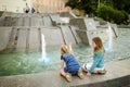 Two cute little girls playing by city fountain on hot and sunny summer day. Children having fun with water in summer Royalty Free Stock Photo