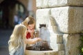 Two cute little girls playing with a drinking water fountain on warm and sunny summer day Royalty Free Stock Photo