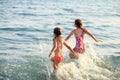 Two Cute Little Girls playing with waves by the Sea at sunset.  Summer Sunny Day, Ocean Coast, happy Kids concept, soft focused Royalty Free Stock Photo