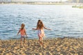 Two Cute Little Girls running with sand by the Sea Waves at sunset. Summer Sunny Day, Ocean Coast, happy Kids concept Royalty Free Stock Photo