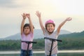 Two cute little girls smiling and posing together in summer garden. Happy kid riding kick scooter in the park. Healthy sports and Royalty Free Stock Photo