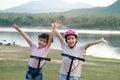 Two cute little girls smiling and posing together in summer garden. Happy kid riding kick scooter in the park. Healthy sports and Royalty Free Stock Photo