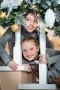 Two cute little girls on the stairs, looking over the railing. sisters waiting for a surprise for christmas