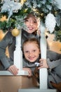 Two cute little girls on the stairs, looking over the railing. sisters waiting for a surprise for christmas