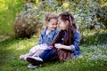 Two cute little girls tell some secrets each over while sitting on the grass in a spring park Royalty Free Stock Photo