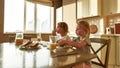 Two cute little kids eating toasted bread with chocolate butter for breakfast or lunch while sitting at the table in the Royalty Free Stock Photo