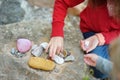 Two cute little sisters collecting beautiful stones on a pebble beach