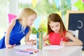 Two cute little sisters drawing with colorful pencils at a daycare Royalty Free Stock Photo