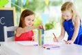 Two cute little sisters drawing with colorful pencils at a daycare. Creative kids painting together. Royalty Free Stock Photo