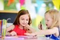 Two cute little sisters drawing with colorful pencils at a daycare. Creative kids painting together. Royalty Free Stock Photo