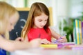 Two cute little sisters drawing with colorful pencils at a daycare. Creative kids painting together. Royalty Free Stock Photo