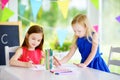 Two cute little sisters drawing with colorful pencils at a daycare. Creative kids painting together. Royalty Free Stock Photo