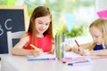 Two cute little sisters drawing with colorful pencils at a daycare. Creative kids painting together. Royalty Free Stock Photo