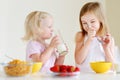 Two cute little sisters eating cereal in a kitchen Royalty Free Stock Photo