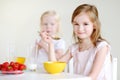 Two cute little sisters eating cereal in a kitchen Royalty Free Stock Photo