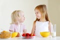 Two cute little sisters eating cereal in a kitchen Royalty Free Stock Photo