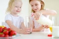 Two cute little sisters eating cereal in a kitchen Royalty Free Stock Photo