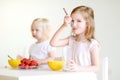 Two cute little sisters eating cereal in a kitchen Royalty Free Stock Photo