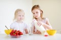 Two cute little sisters eating cereal in a kitchen Royalty Free Stock Photo