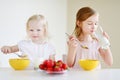 Two cute little sisters eating cereal in a kitchen Royalty Free Stock Photo