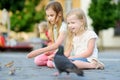 Two cute little sisters feeding birds on summer day. Children feeding pigeons and sparrows outdoors. Royalty Free Stock Photo