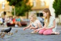 Two cute little sisters feeding birds on summer day. Children feeding pigeons and sparrows outdoors. Royalty Free Stock Photo