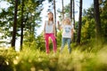 Two cute little sisters having fun during forest hike on beautiful summer day. Active family leisure with kids. Royalty Free Stock Photo