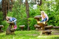Two cute little sisters having fun on giant wooden mushrooms Royalty Free Stock Photo