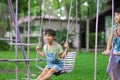 Two cute little sisters having fun playing in the playground during summer. Cute little girl swinging in the playground with a Royalty Free Stock Photo
