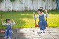 Two cute little sisters having fun on a swing together in a beautiful summer garden on a warm and sunny day outdoors. Active Royalty Free Stock Photo