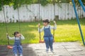 Two cute little sisters having fun on a swing together in a beautiful summer garden on a warm and sunny day outdoors. Active Royalty Free Stock Photo