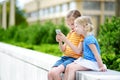 Two cute little sisters playing outdoor mobile game on their smart phones Royalty Free Stock Photo