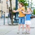 Two cute little sisters playing outdoor mobile game on their smart phones Royalty Free Stock Photo