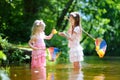 Two cute little sisters playing in a river catching rubber ducks with their scoop-nets Royalty Free Stock Photo