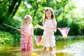Two cute little sisters playing in a river catching rubber ducks with their scoop-nets Royalty Free Stock Photo