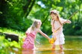 Two cute little sisters playing in a river catching rubber ducks with their scoop-nets Royalty Free Stock Photo