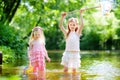 Two cute little sisters playing in a river catching rubber ducks with their scoop-nets Royalty Free Stock Photo