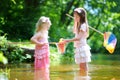 Two cute little sisters playing in a river catching rubber ducks with their scoop-nets Royalty Free Stock Photo