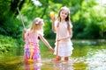 Two cute little sisters playing in a river catching rubber ducks with their scoop-nets Royalty Free Stock Photo